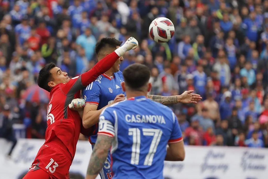 Cristopher Toselli puñetea el balón ante el salto de Ignacio Tapia en el Superclásico 194. (Felipe Zanca/Photosport).