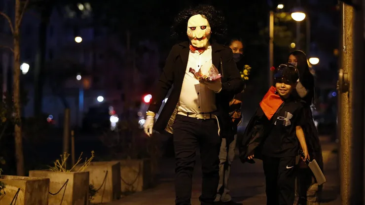 Niños disfrutan la noche de Halloween pidiendo dulces junto a sus padres en la comuna de Santiago.
