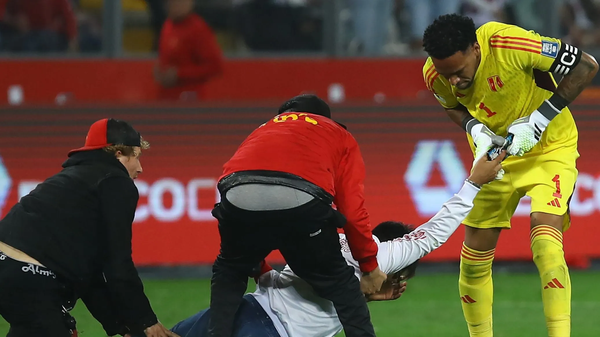 Pedro Gallese forcejea para quedarse con el teléfono móvil del hincha invasor de Perú que buscaba una foto con Messi. (Leonardo Fernandez/Getty Images).