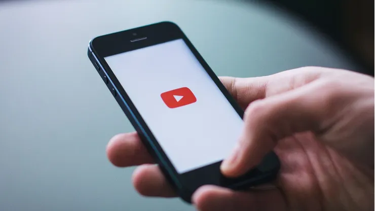 Persona sostiene un teléfono mientras abre la app de YouTube.