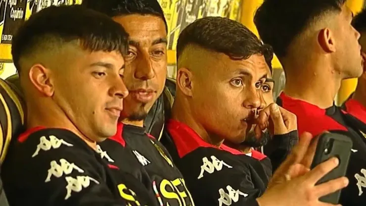Montecinos y Tiznado mirando el celular en la banca