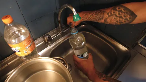 Persona juntando agua durante un corte de agua.