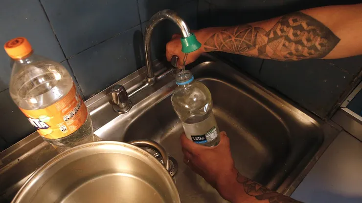 Persona juntando agua durante un corte de agua.