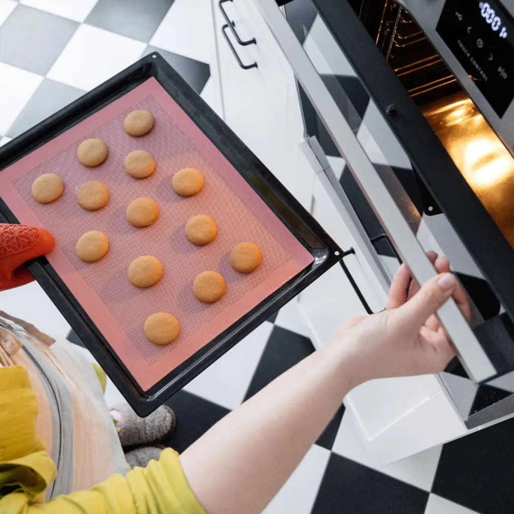 Mujer poniendo galletas en el horno