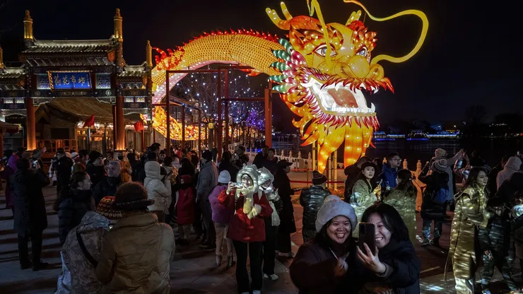 Un grupo de personas se reúne en torno a una gran figura de dragón con motivo del Año Nuevo Chino y la Fiesta de la Primavera en un parque de una zona histórica local el 9 de febrero de 2024 en Pekín, China.