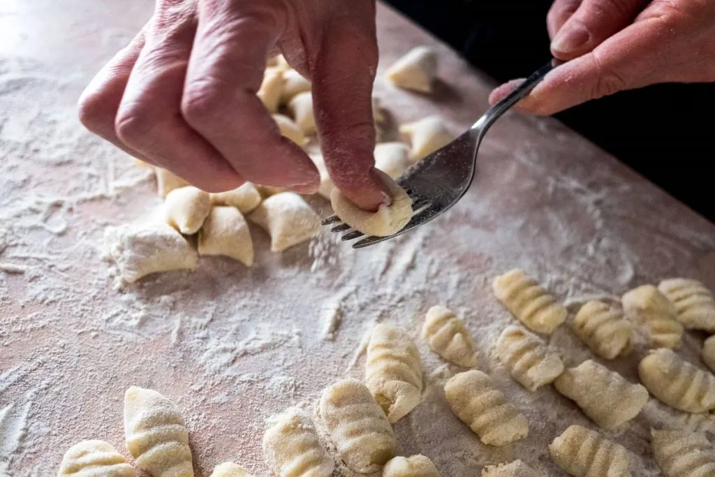 Una persona marca los gnocchi con un tenedor antes de cocinarlos en agua