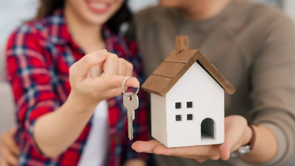 Pareja sostiene las llaves de una casa nueva