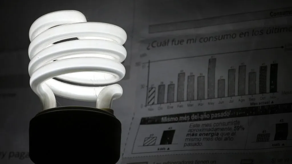 Una ampolleta encendida al lado de una cuenta de la luz