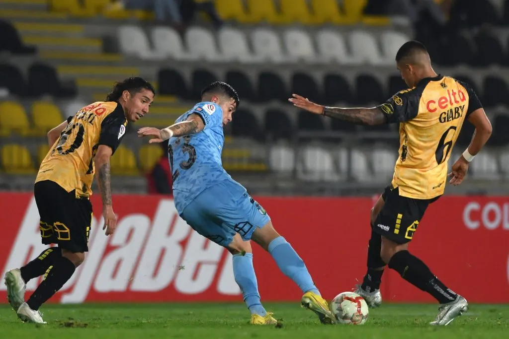Dylan Glaby lucha un balón ante la mirada de Luciano Cabral, su socio en el mediocampo aurinegro. (Alejandro Pizarro Ubilla/Photosport).