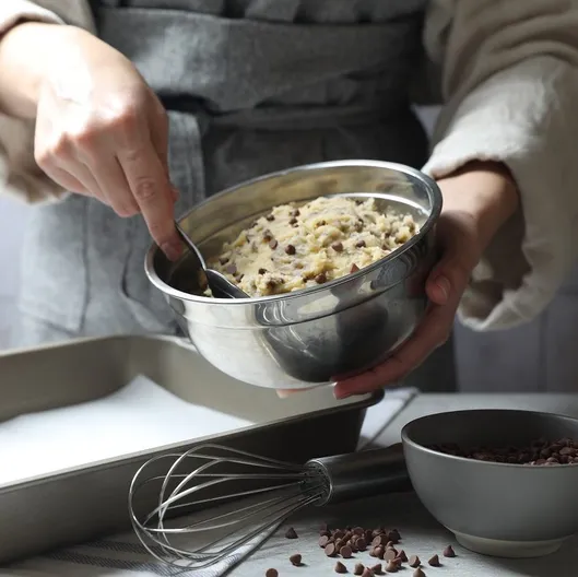 Una persona integra con una cuchara la mezcla para las galletas con chips de chocolate