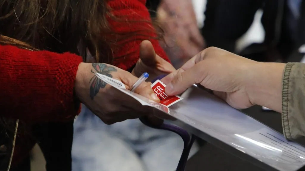 Un vocal de mesa entrega el voto y estampilla a un electoral.