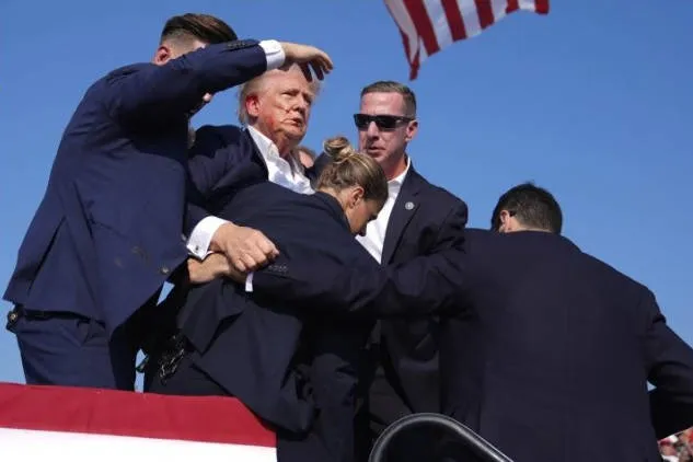 Momento en que Trump es sacado del acto tras el disparo. Foto: Imago.