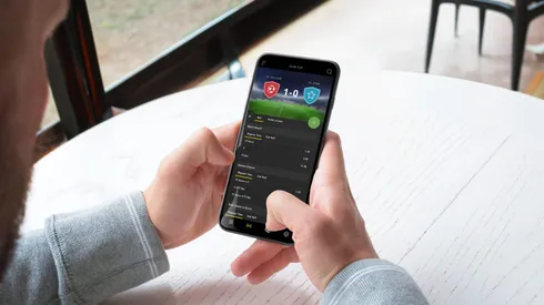 2R9G0PF Man bets live on a football match through a mobile phone app. The concept of online sports betting. A modern app for mobile platforms