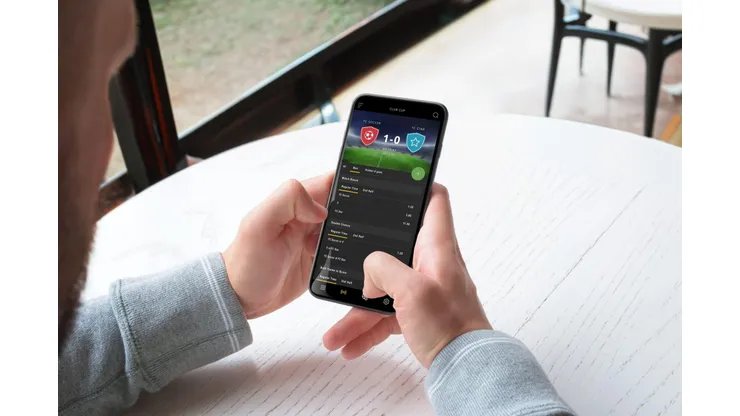 2R9G0PF Man bets live on a football match through a mobile phone app. The concept of online sports betting. A modern app for mobile platforms