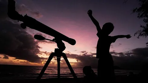 Un niño se prepara para ver el cielo con su telescopio.