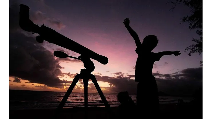 Un niño se prepara para ver el cielo con su telescopio.