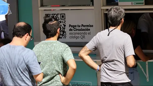 Personas hacen fila para pagar el permiso de circulación.