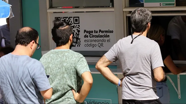 Personas hacen fila para pagar el permiso de circulación.