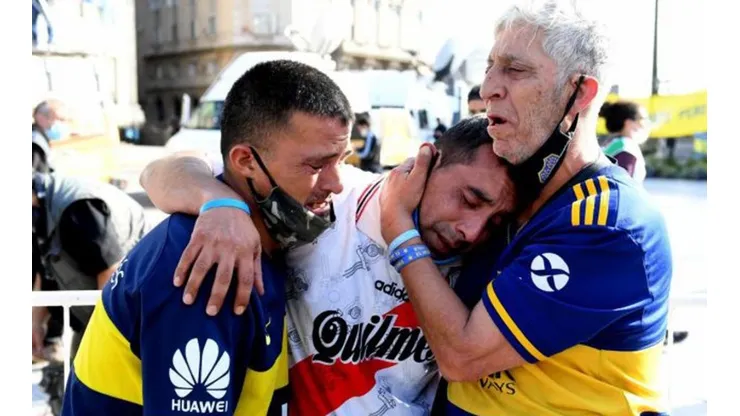 Hinchas de Boca Juniors y River Plate lloran abrazados la muerte de Maradona.