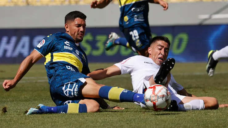Federico Martínez y Osvaldo Bosso pelean por el balón en el suelo en el encuentro entre Everton y Ñublense, en la primera rueda del Campeonato Nacional 2024.