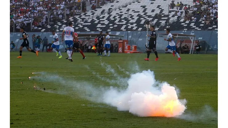 Una bengala cae sobre el césped del Estadio Monumental