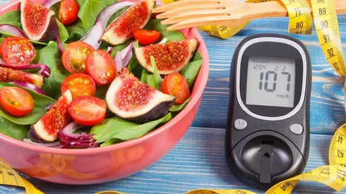 Fruit and vegetable salad and glucometer with tape measure, concept of diabetes, slimming and healthy nutrition