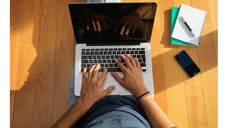 Workspace at home. Student working with a laptop on the floor.