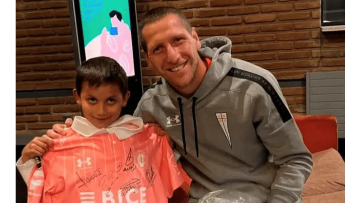 El pequeño Luciano compartiendo con Aued, con el regalo de la camiseta de Universidad Católica.
