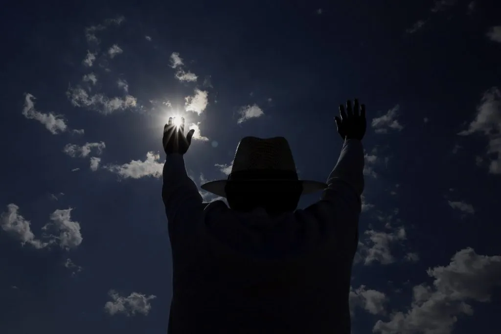 Contraluz de una persona que levanta los brazos para cargarse de energía positiva durante el equinoccio de primavera