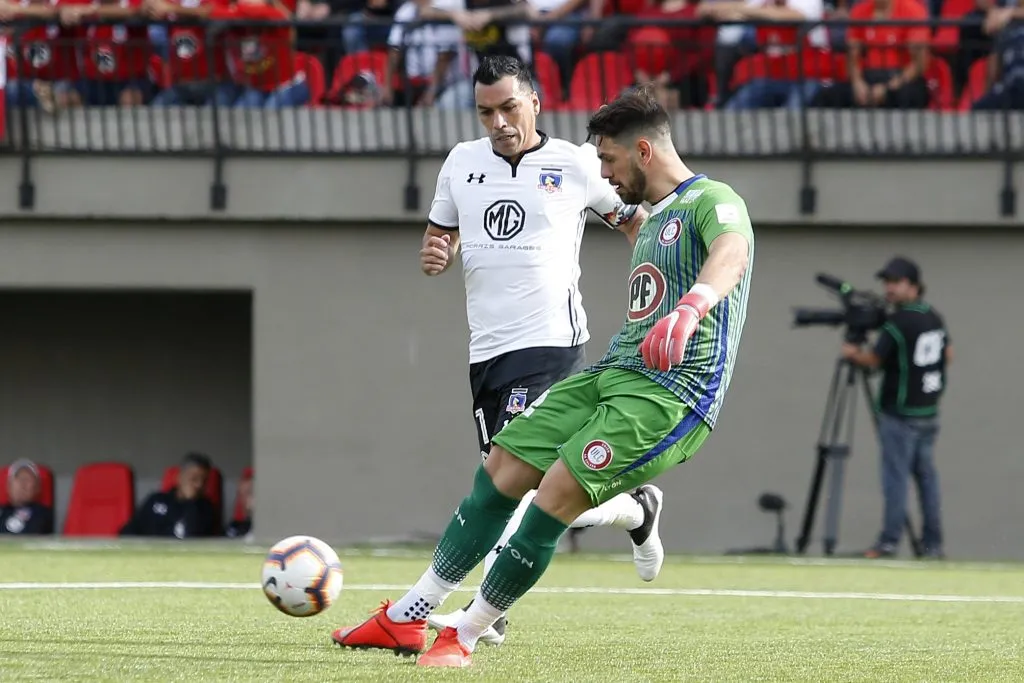 Augusto Batalla despeja ante la presión de Esteban Paredes. (Raul Zamora/Photosport).