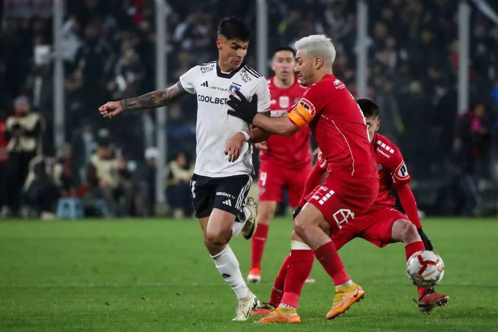 Lorenzo Reyes ante Erick Wiemberg en un duelo entre Colo Colo y Ñublense. (Jonnathan Oyarzun/Photosport).