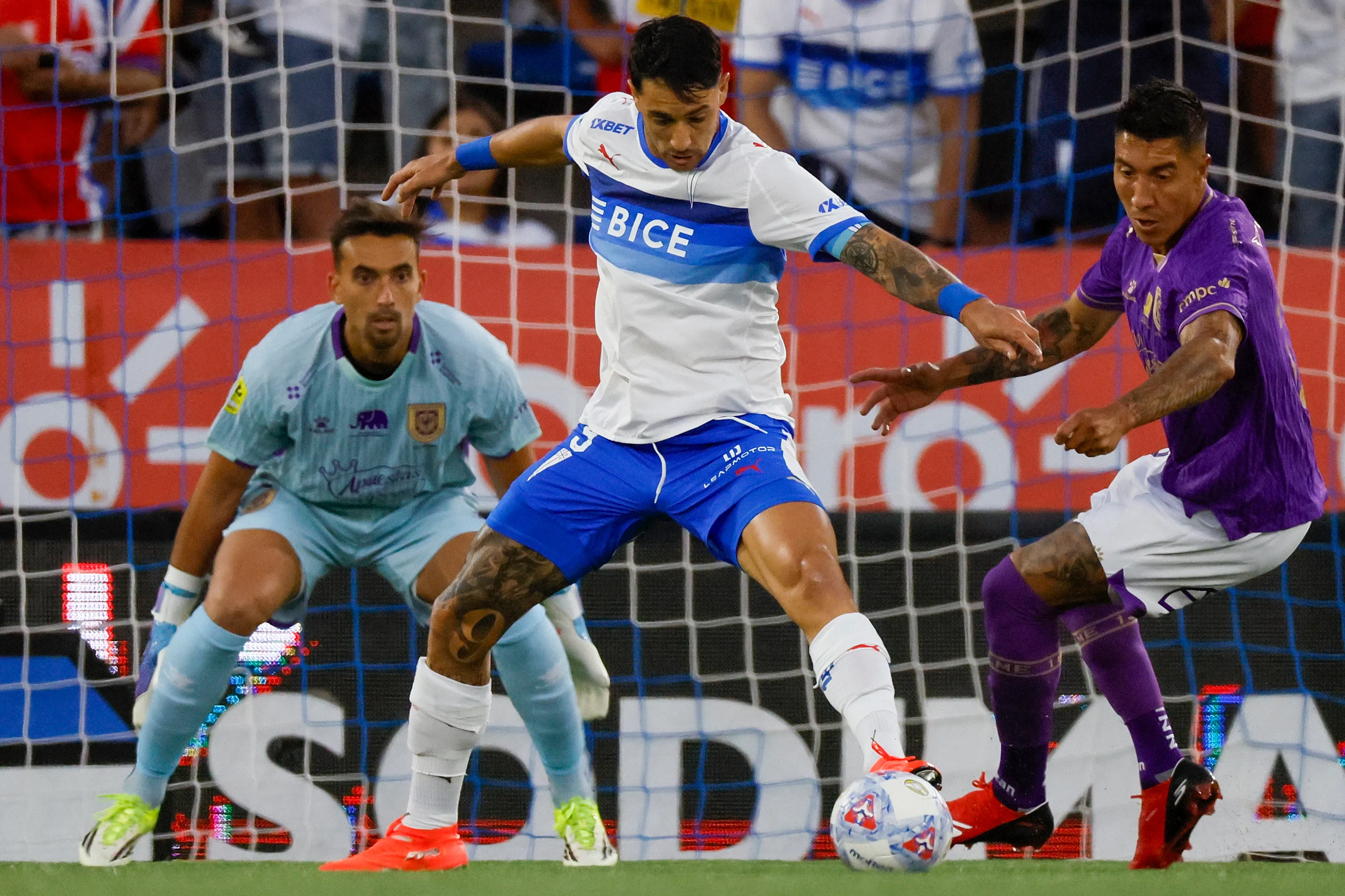 César Dutra observa a Cristián Suárez intentar marcar a Fernando Zampedri, autor de un gol y una asistencia ante el León de Collao. (Andres Pina/Photosport).