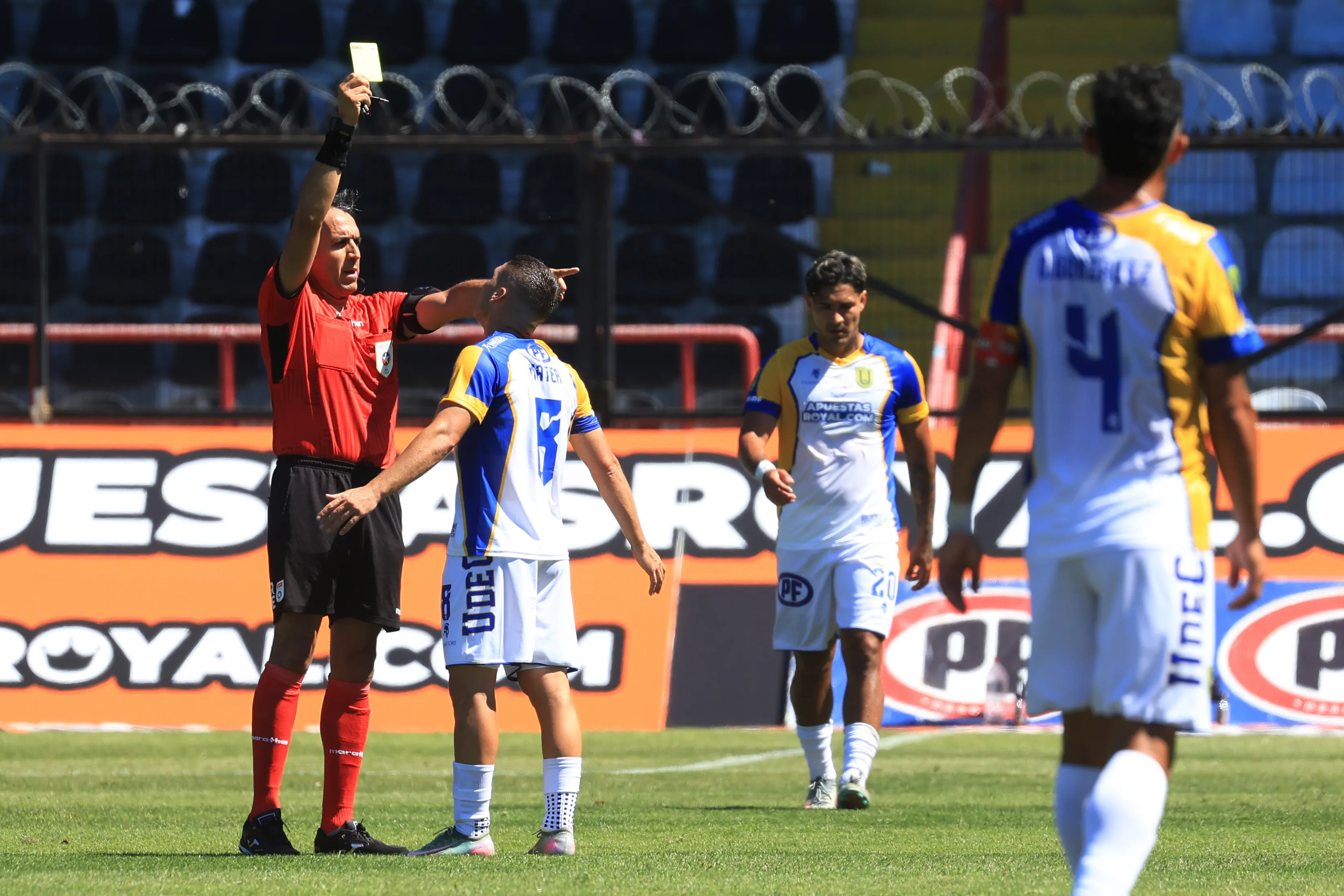 Jona arbitró el duelo que la UdeC le ganó a Coquimbo Unido. En la foto amonesta al argentino-sirio Facundo Mater. (Eduardo Fortes/Photosport).