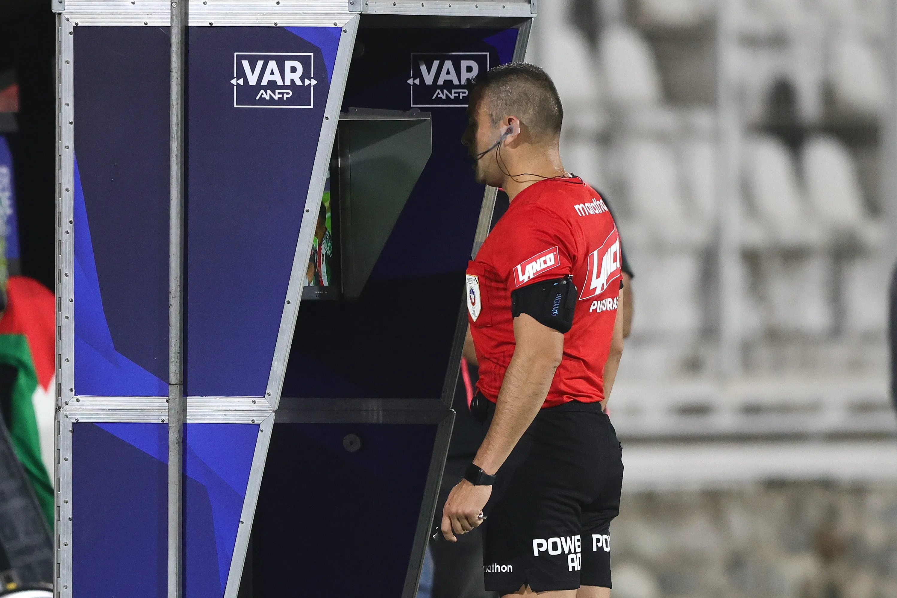 El árbitro Diego Flores conversado con el VAR en U de Chile vs Palestino. Foto: Felipe Zanca/Photosport