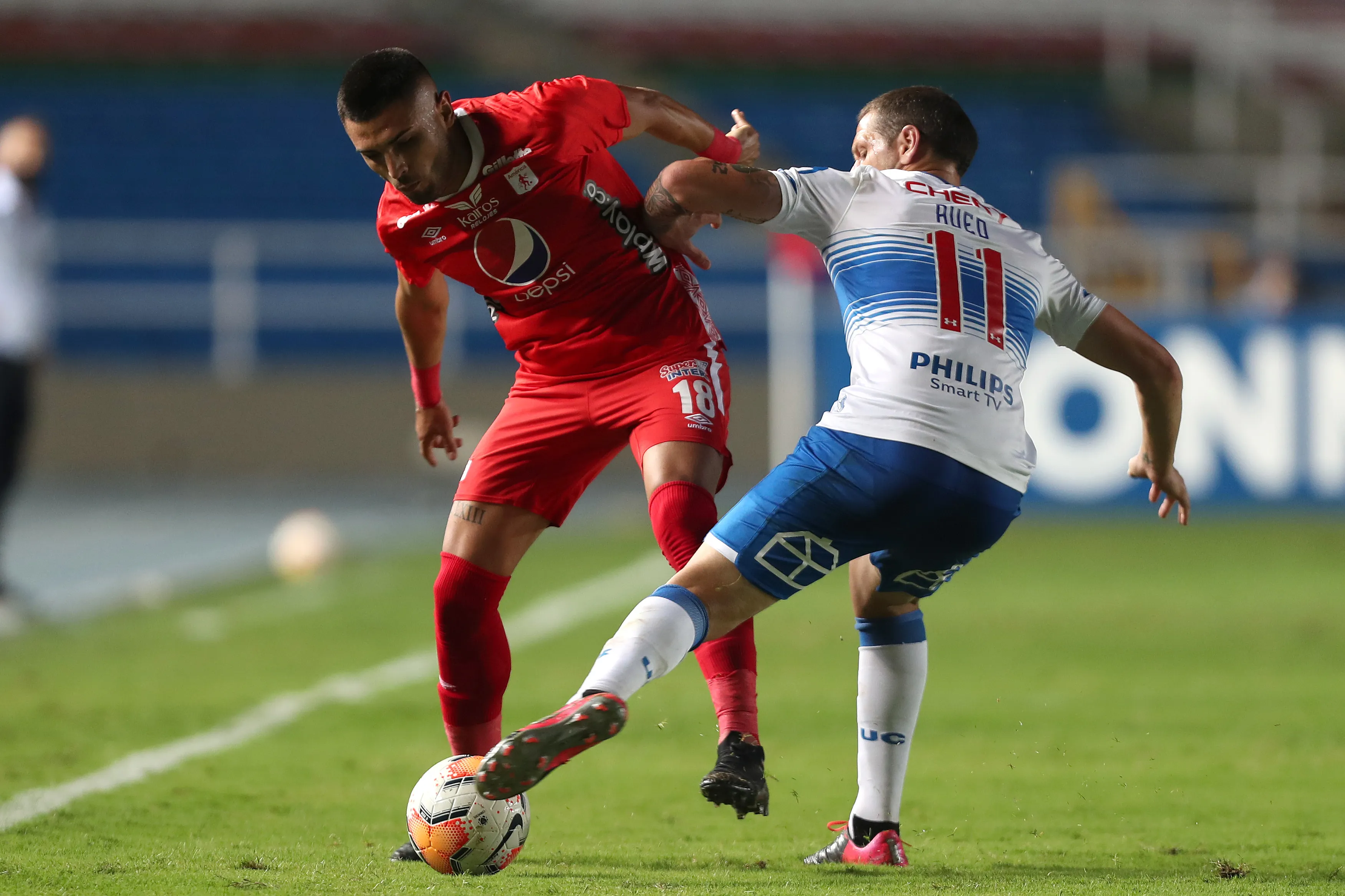 Rodrigo Ureña ante Luciano Aued en un duelo internacional entre América de Cali y Universidad Católica. (Fernando Vergara – Pool/Getty Images)