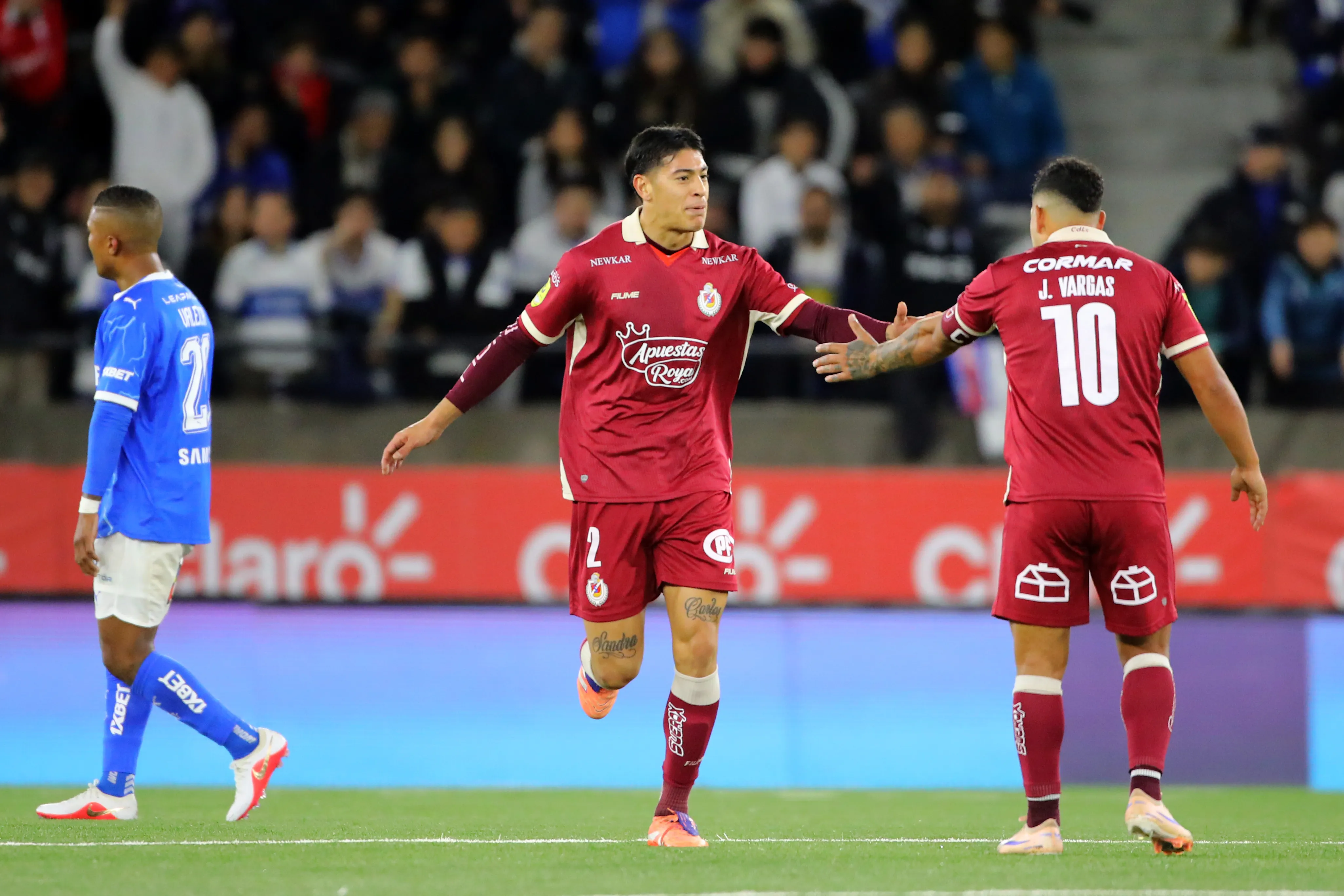 Jeisson Vargas felicita a Gonzalo Figueroa por uno de sus goles frente a los Cruzados. (Jonnathan Oyarzun/Photosport).
