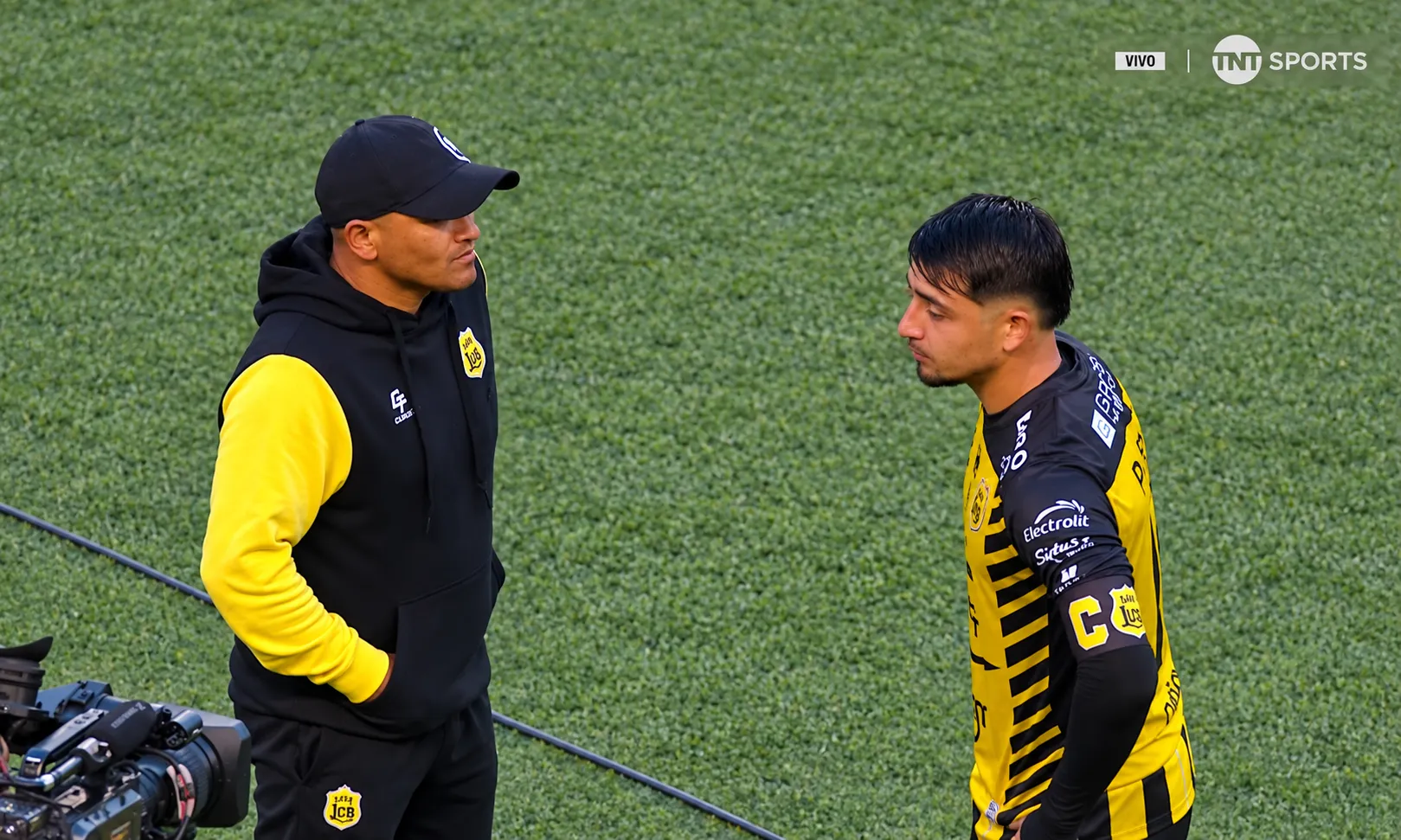 Sebastián Parada, el capitán de los Canarios, habla con Chupete Suazo. (Captura TNT Sports retocada con ChatGPT).