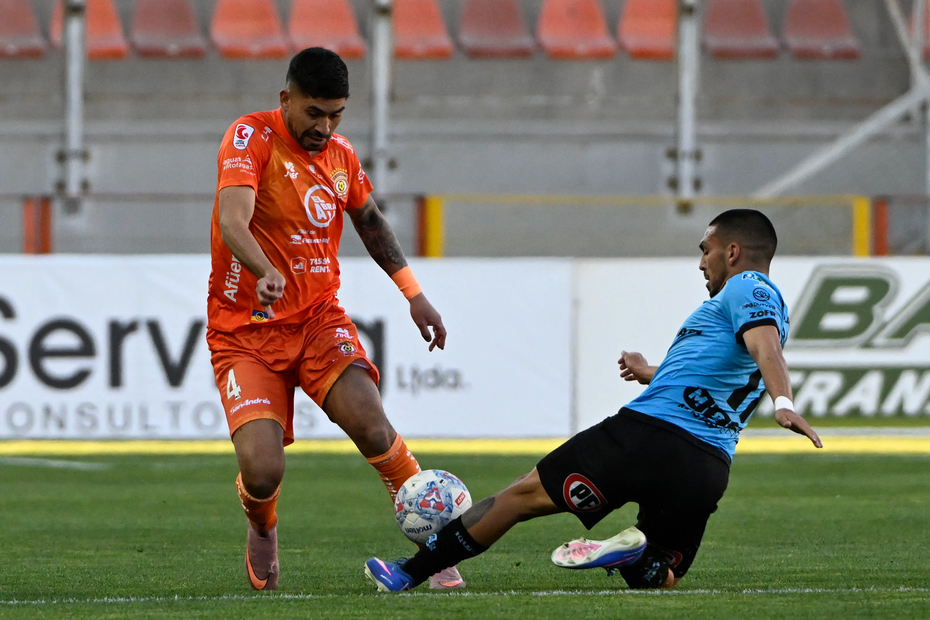Bastián San Juan lucha un balón con César González en un duelo ante Deportes Iquique. (Pedro Tapia/Photosport).