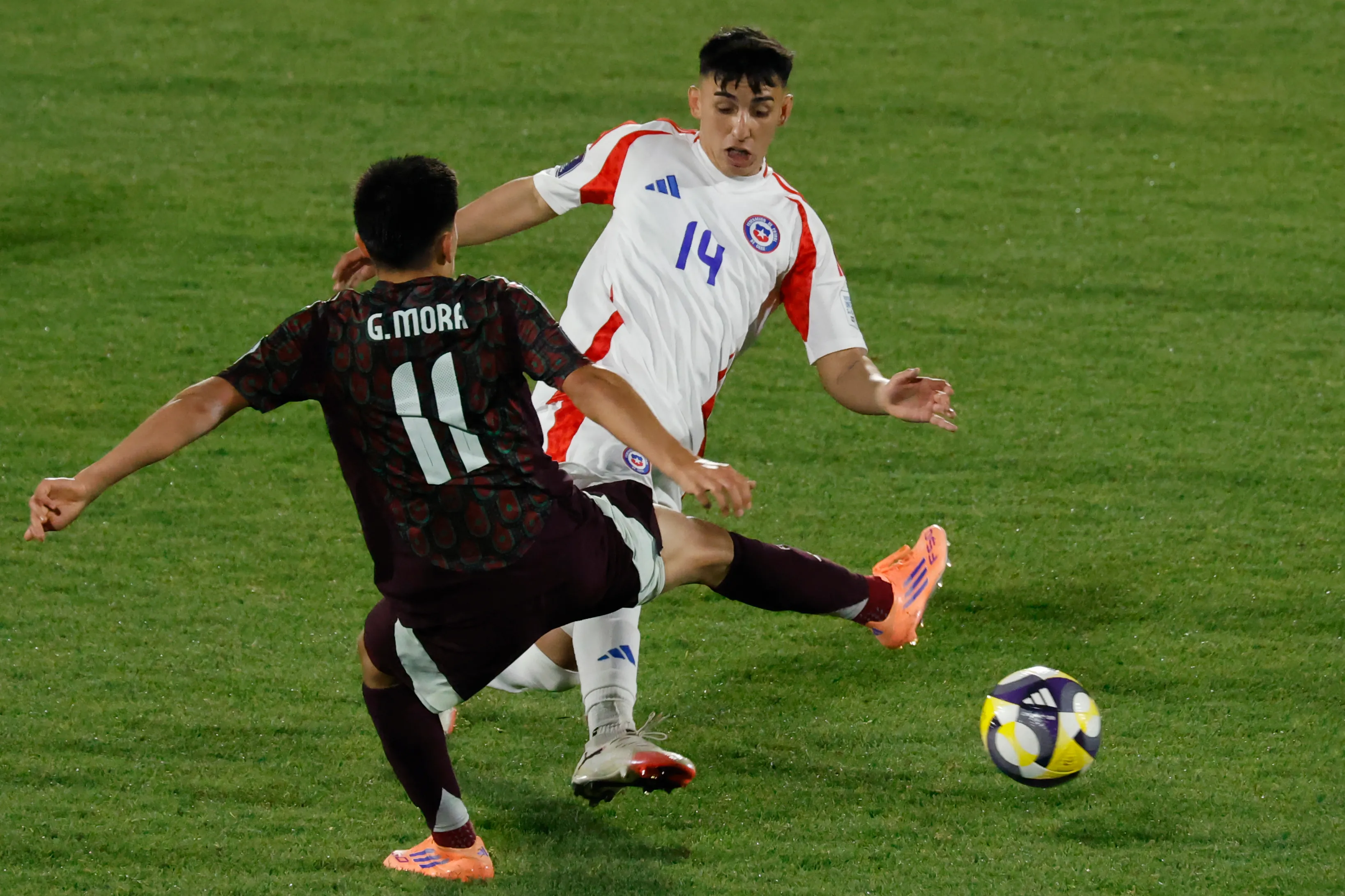 Gilberto Mora en acción ante Chile. Trata de frenar a Lautaro Millán. (Sebastian Cisternas/Photosport).